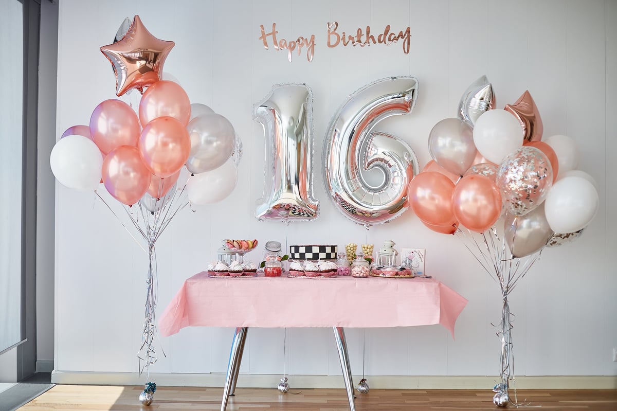 Milestone birthday party styling with a candy bar table and gold balloon number 16 decor