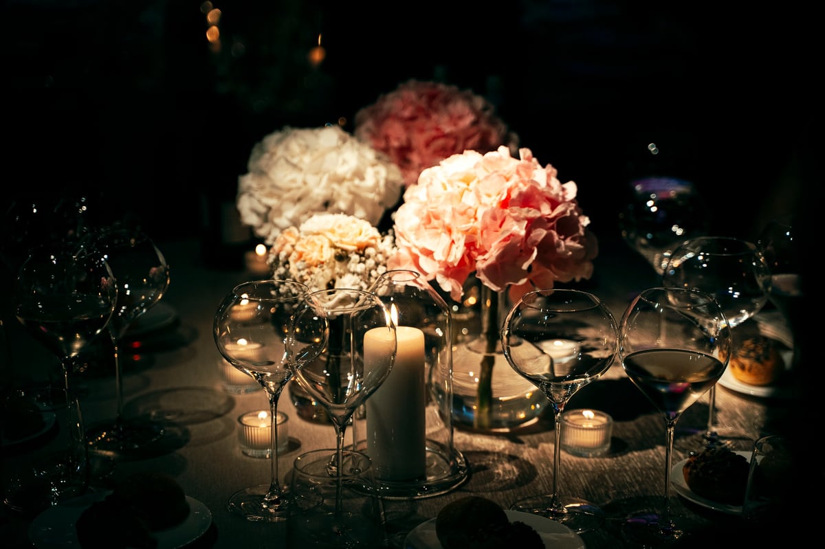 Custom centerpiece with florals, glassware and candles on an elegantly set event table