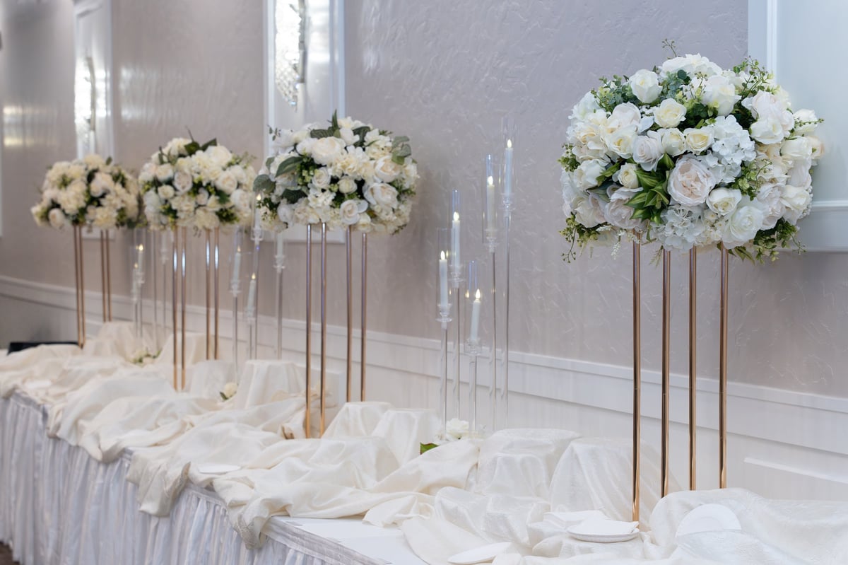Elegant tablescape styling with white tablecloths, floral arrangements and candle centerpieces for events