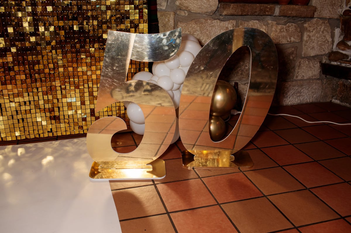 Milestone birthday party decor with gold balloon number and sequin backdrop styling