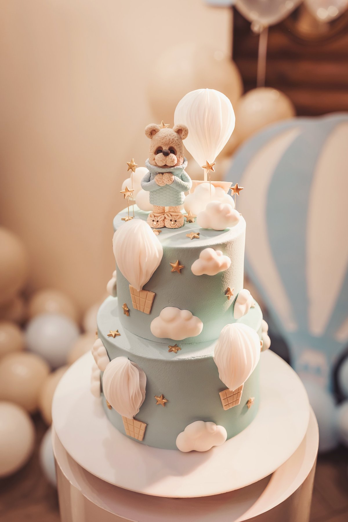 Baby shower celebration cake with teddy bear and hot air balloon decor and themed balloons